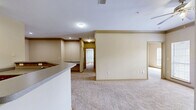 Located at 100 Wesley Stonecrest Circle in Stonecrest, GA, this two-bedroom, two-bathroom residence offers a well-organized single-floor layout with a thoughtful mix of comfort and functionality. The kitchen is equipped with rich cherry-toned cabinetry, a tile backsplash, black appliances including a range and refrigerator, and light countertops — all set atop tile flooring that extends through the main utility areas. Both bedrooms feature plush wall-to-wall carpeting and large windows that invite generous natural light and outdoor views. The spacious primary bedroom includes a walk-in closet with built-in shelving for ample storage. The living area is highlighted by crown molding, a ceiling fan with light fixture, and direct access to an outdoor balcony or patio through a glass-paneled door. Both bathrooms are finished with tile flooring and soaking tubs; one features decorative diamond-tile accents along the surround, adding a distinct design detail. Each bedroom is served by its own closet, and the layout includes two dedicated closet spaces throughout. The warm, neutral color palette and carpeted living spaces contribute to an inviting and comfortable overall ambiance.