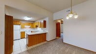 Located at 3866 Carmona Dr in Newburgh, Indiana, this single-floor home offers a practical and comfortable layout designed for easy living. The kitchen is a functional centerpiece, featuring warm oak cabinetry with ample upper and lower storage, light countertops, a double stainless steel sink, and white appliances including a range and refrigerator. Light tile flooring runs throughout the kitchen, which flows seamlessly into the adjoining living and dining areas via an open peninsula—ideal for both everyday use and entertaining. The living and dining spaces are finished with neutral carpet and benefit from vaulted ceilings that lend a sense of openness and height. A chandelier and ceiling fan provide both ambient and functional lighting, while a window at the entry brings in natural light and outdoor views. The bedrooms are carpeted and neutrally appointed, each with windows that allow natural light to filter in. The bathroom is thoughtfully designed with accessibility in mind, featuring grab bars in the walk-in shower, tile flooring, and clean white fixtures. Throughout the home, warm wood-tone trim and doors provide a cohesive aesthetic, complementing the light walls and neutral palette that make this a welcoming, move-in-ready space.
