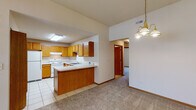 Located at 3866 Carmona Dr in Newburgh, Indiana, this single-floor home offers a practical and comfortable layout designed for easy living. The kitchen is a functional centerpiece, featuring warm oak cabinetry with ample upper and lower storage, light countertops, a double stainless steel sink, and white appliances including a range and refrigerator. Light tile flooring runs throughout the kitchen, which flows seamlessly into the adjoining living and dining areas via an open peninsula—ideal for both everyday use and entertaining. The living and dining spaces are finished with neutral carpet and benefit from vaulted ceilings that lend a sense of openness and height. A chandelier and ceiling fan provide both ambient and functional lighting, while a window at the entry brings in natural light and outdoor views. The bedrooms are carpeted and neutrally appointed, each with windows that allow natural light to filter in. The bathroom is thoughtfully designed with accessibility in mind, featuring grab bars in the walk-in shower, tile flooring, and clean white fixtures. Throughout the home, warm wood-tone trim and doors provide a cohesive aesthetic, complementing the light walls and neutral palette that make this a welcoming, move-in-ready space.