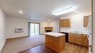 Located at 4723 Southridge Ct in Eau Claire, Wisconsin, this single-floor, 2-bedroom, 1-bathroom home offers a practical and comfortable layout with warm, consistent finishes throughout. The open-concept kitchen and living area serves as the heart of the home, with rich hardwood-style flooring in the kitchen transitioning to plush carpet in the living area. The kitchen is well-appointed with oak cabinetry, a center island with a white countertop, ample counter space, a double sink, dishwasher, electric range, and a full-size refrigerator. A dedicated laundry area adds everyday convenience. The living room is bright and inviting, featuring a wood-trimmed fireplace and a sliding glass door that lets in natural light and provides outdoor access. Both bedrooms are carpeted and include built-in closets with bi-fold doors; the primary bedroom is generously sized and features a ceiling fan and window. The full bathroom is finished with oak vanity cabinetry, a white countertop, a single sink with mirror, and hardwood-style flooring. Throughout the home, five closets provide exceptional storage. Neutral wall tones and warm wood trim details create a cohesive, welcoming atmosphere throughout this well-designed Eau Claire residence.