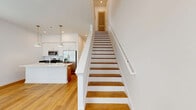 Located at 1280 Oconee St in Athens, GA, this modern two-story home offers three bedrooms, four bathrooms, and a thoughtfully designed layout spread evenly across two floors. The open-concept main floor combines the kitchen and living room into a bright, welcoming space anchored by warm hardwood-style flooring that runs throughout the home. The kitchen stands out with its large central island featuring an integrated sink, crisp white shaker cabinetry, dark quartz countertops, and stainless steel appliances including a refrigerator with ice maker, electric range, and microwave. Pendant lighting with gold accents adds a contemporary touch above the island. The living area benefits from large windows with white blinds, allowing abundant natural light and views of the surrounding greenery. A staircase connects to the upper floor, where the bedrooms are situated. The primary bedroom is generously sized, featuring tall ceilings, wide windows, and access to a closet. Additional bedrooms are bright and well-proportioned, each with hardwood-style floors and natural light. The four bathrooms maintain a clean, modern aesthetic with white subway tile shower surrounds, white vanities with undermount sinks, and warm wood flooring. The home's consistent white palette, modern fixtures, and quality finishes create a cohesive, contemporary feel throughout.