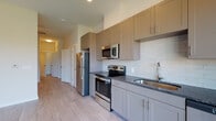 Located at 240 Grant St SE in Atlanta's vibrant Grant Park neighborhood, this modern single-floor unit offers a thoughtfully designed open layout with contemporary finishes throughout. Light wood-style flooring runs seamlessly across the living and kitchen areas, complementing the bright, neutral color palette and creating a clean, cohesive aesthetic.

The kitchen is a standout feature, equipped with stainless steel appliances including a range, microwave, refrigerator, and dishwasher. Sleek gray shaker-style cabinetry pairs elegantly with dark granite countertops, while a white subway tile backsplash adds a classic touch. A large window alongside the kitchen allows natural light to pour in and offers views of the surrounding greenery.

The living area is open and airy, benefiting from ceiling fans and generous windows that provide abundant natural light and outdoor views. The bedroom features the same light flooring and connects to the well-lit, shared living space.

The bathroom is finished with large-format tile on both the floors and shower walls, and includes a sleek glass-enclosed walk-in shower with a built-in bench, reflecting a modern and spa-inspired design sensibility.

A dedicated in-unit laundry closet houses a stacked washer and dryer, adding everyday convenience. Overall, the space presents a polished, move-in-ready environment with modern amenities in a well-connected Atlanta location.