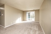 This two-bedroom, one-bathroom single-floor unit in Altoona, Iowa offers a practical and comfortable layout. The open living room is a highlight of the space, featuring plush carpeting, neutral beige walls, a textured ceiling, and a sliding glass door that floods the room with natural light and provides outdoor views. The kitchen is efficiently designed with warm wood cabinetry, dark granite-style countertops, a double-basin sink, a dishwasher, and durable hardwood-style flooring — offering ample storage and workspace. Both bedrooms are carpeted and feature ceiling fans with light fixtures, natural light from windows, and generous closet space. The primary bedroom includes a dedicated closet with a hanging rod, while a separate walk-in closet with dual hanging rods provides additional storage. The bathroom is clean and functional, appointed with tile flooring in a classic pattern, a full soaking tub with shower, white surround, and a vanity with a countertop sink. A hallway connects the living areas to the private spaces, completing a well-organized and efficient floor plan suited for comfortable everyday living.