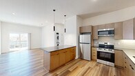 Located at 220 N Walton Blvd in Bentonville, Arkansas, this thoughtfully designed 2-bedroom, 1-bathroom residence offers a clean, modern aesthetic across a well-utilized single floor. Warm, multi-tone wood-look flooring flows seamlessly throughout every room, complementing the crisp white walls and contemporary finishes.

The open-concept kitchen and living area serves as the heart of the home. The kitchen is outfitted with flat-front cabinetry in a natural tan finish, dark quartz countertops, a classic subway tile backsplash with under-cabinet lighting, stainless steel appliances including a refrigerator, range, microwave, and dishwasher, and a matte black faucet. A central island with additional cabinetry provides extra prep space and storage. An in-unit stacked washer and dryer is conveniently tucked nearby. The open living area features recessed lighting and a clean, versatile layout.

Both bedrooms are well-proportioned, each with ceiling fans, generous closet storage — including a full built-in wardrobe — and windows that invite natural light. The primary bedroom offers a comfortable, spacious feel.

The bathroom is finished with a dual-sink vanity featuring dark stone countertops, warm wood cabinetry, matte black fixtures, and a frameless mirror, all reflecting the home's cohesive modern design language.