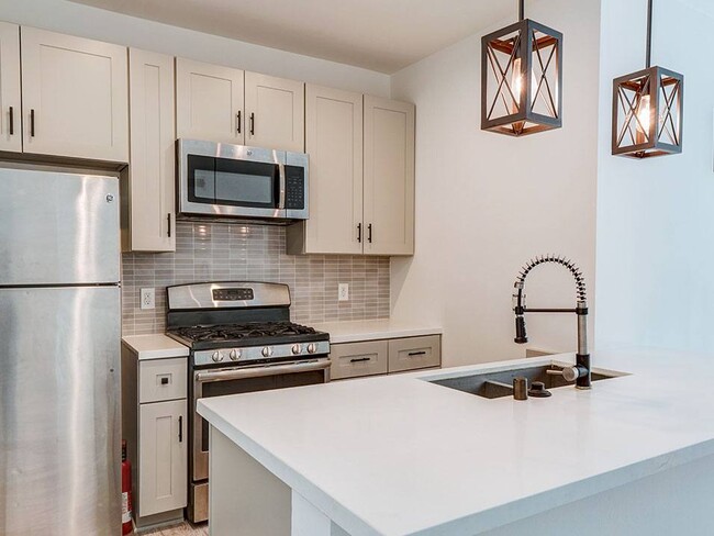 Kitchen with new modern styled faucet, stainless steel appliances, and refrigerator. - Bonita Terrace