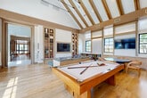 Located at 400 E 7th St in Frederick, Maryland, this thoughtfully designed clubhouse spans a generous single floor, offering residents a sophisticated and versatile community retreat. The interior is unified by a warm, contemporary aesthetic characterized by natural white oak flooring, wood-paneled ceilings and walls, and a refined neutral palette accented with rich earth tones.

The welcoming entry area features a sleek reception counter, a curated decorative wall shelf, and a built-in upholstered banquette, setting an inviting tone from the outset. The Great Room commands immediate attention with its soaring vaulted ceiling supported by elegant exposed wood beams, built-in bookshelves flanking a large-screen TV, and a full-size billiards table—making it the social centerpiece of the clubhouse. Oversized black-framed windows flood the space with natural light and offer views of the surrounding streetscape.

A dedicated lounge area provides a quieter retreat, furnished with vibrant terracotta daybeds, sculptural artwork, and floor-to-ceiling windows. The co-working and dining area offers a mix of banquette seating with striped cushions, marble bistro tables, and communal tables beneath a modern chandelier, with a private phone room accessible via glass-paned doors. A fully equipped gym rounds out the amenities, supporting an active lifestyle within this polished community hub.