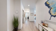 This thoughtfully designed 2-bedroom, 2-bathroom single-floor residence offers a cohesive open-concept layout that seamlessly connects the living, dining, and kitchen areas. Light wood-look flooring flows throughout the main living spaces, complemented by crisp white walls and recessed lighting that create a bright, airy atmosphere.

The kitchen is a standout feature, showcasing sleek gray cabinetry, white quartz countertops, a tile backsplash, and a full suite of stainless steel appliances. A central island with seating provides both additional prep space and a casual dining option, while stylish pendant lights add a contemporary touch. The adjacent dining area benefits from a wall of windows dressed in linen curtains, filling the space with abundant natural light.

The primary bedroom is generously sized, featuring plush carpeting, a ceiling fan, and large windows. It includes access to a dedicated closet with built-in shelving. The second bedroom is equally well-proportioned and bright. Both bathrooms are finished with clean, modern fixtures and light wood-look flooring. A welcoming entry hallway with recessed lighting leads residents through the thoughtfully arranged floor plan, connecting each room with ease and functionality.