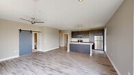 This well-appointed 2-bedroom, 2-bathroom residence in Pittsburgh, PA offers a thoughtfully designed single-level layout with modern finishes throughout. The open-concept living and kitchen area serves as the heart of the home, featuring light wood-look flooring, a ceiling fan, and a striking sliding barn door that adds a contemporary touch. Large windows flood the living space with natural light and frame views of the surrounding neighborhood.

The kitchen is outfitted with dark, rich cabinetry, light quartz countertops, stainless steel appliances including a refrigerator, built-in microwave, and dishwasher, along with a central island that provides additional prep and seating space. A tall window above the counter extends the bright, airy feel.

Both bedrooms are carpeted and receive abundant natural light through well-positioned windows with neighborhood views. The primary bedroom connects to an en-suite bathroom featuring a dual-sink vanity with dark cabinetry, quartz countertops, and wood-look tile flooring. The second bathroom offers a glass-enclosed shower, single-sink vanity, and matching finishes.

A hallway connects the rooms efficiently, lined with louvered double closet doors that provide generous storage. The neutral color palette and consistent modern design language create a cohesive, comfortable ambiance throughout the home.