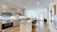 Located at 9302 Fry Rd in Cypress, TX, this thoughtfully designed one-bedroom, one-bathroom residence offers a clean, modern aesthetic throughout its efficiently organized single-floor layout. Light wood-tone flooring flows seamlessly across the entire space, complemented by crisp white walls and recessed lighting that create a bright, welcoming atmosphere.

The open-concept kitchen is a standout feature, showcasing contemporary flat-panel cabinetry in a warm taupe finish, granite countertops, a subway tile backsplash, and a full suite of stainless steel appliances including a refrigerator, range, microwave, and dishwasher. A central island with bar seating connects the kitchen to the combined dining and living area, which is bathed in natural light from multiple windows and features a ceiling fan overhead. A private exterior door in the living area adds convenient access to the outdoors.

A hallway off the main living space leads to the bedroom, which offers two windows, a ceiling fan, and wood-look flooring. An adjacent walk-in closet provides ample storage with dual hanging rods and shelving. The full bathroom features a granite-topped vanity with a taupe cabinet, large-format tile surround in the tub/shower combination, and wood-look flooring consistent with the rest of the home.