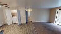 Located in Kent, Washington, this single-floor unit at 11034 SE 240th Pl offers a well-organized layout designed for comfortable everyday living. The open-concept living and dining area combines plush carpeting with wood-look vinyl flooring, creating a clear visual distinction between functional zones. A tile-surround fireplace serves as a focal point in the living area, which also features a sliding glass door that invites natural light and provides outdoor access. Baseboard heating is present throughout, ensuring consistent warmth across all rooms.

The kitchen is efficiently designed with white cabinetry extending to the upper walls for ample storage, light-toned countertops, and white appliances including a refrigerator, electric range, and under-cabinet range hood. A peninsula counter separates the kitchen from the main living space, adding a practical workspace. A dedicated laundry area with side-by-side washer and dryer units adds notable convenience.

The bedrooms are carpeted and receive natural light through windows fitted with vertical blinds, each equipped with baseboard heaters. The bathroom features wood-look vinyl flooring, a vanity with countertop storage, and a separate water closet for added privacy.