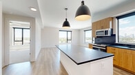 Located at 1350 40th St in Denver, CO, this well-appointed 4-bedroom, 2-bathroom residence offers a thoughtfully designed single-floor layout with modern finishes throughout. The open-concept kitchen and living area serves as the heart of the home, featuring a large center island with a dark countertop, warm wood cabinetry, a dark tile backsplash, and stainless steel appliances. Dual black pendant lights hang above the island, adding an industrial-modern touch. Large windows flood the space with natural light and frame impressive views of the Denver skyline and surrounding greenery. Light wood-plank flooring runs throughout the main living areas, complementing the clean white walls and modern interior doors with matte black hardware. The hallway connects the living spaces to the four bedrooms, each offering generous natural light via large windows with city and landscape views. The primary bedroom features a ceiling fan and plush carpeting, while other bedrooms include hardwood-style flooring. A dedicated closet provides built-in shelving and hanging storage. The two bathrooms are finished with wood-toned vanities, dark countertops, matte black fixtures, and a striking black subway tile surround in the tub and shower area, delivering a cohesive, contemporary aesthetic throughout.