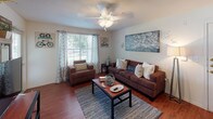 This single-story, 4-bedroom, 4-bathroom home offers a thoughtfully designed layout that maximizes both comfort and functionality. The living room serves as the heart of the home, featuring rich hardwood-style flooring, a ceiling fan, and large windows that welcome an abundance of natural light, creating a warm and inviting atmosphere. The galley-style kitchen is equipped with white cabinetry, a full suite of white appliances including a range, microwave, and dishwasher, along with light countertops and direct access to a dedicated laundry room. The laundry room includes a full-size washer and dryer, built-in shelving, and an electrical panel for added utility. Each of the four bedrooms is carpeted for comfort and features a ceiling fan, natural light from well-positioned windows, and a closet with mirrored sliding doors and built-in shelving for ample storage. The bedrooms also offer space for a desk, making them versatile for both rest and work. The bathrooms are clean and functional, each featuring a tub-shower combination, vanity with white cabinetry, a large mirror, and hardwood-style flooring. Overall, this home presents a practical and comfortable living environment suited for shared or family living.