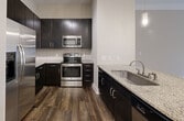 This contemporary 780-square-foot apartment in Charlotte, NC, offers a thoughtful blend of style and functionality. The open-concept living area seamlessly integrates the kitchen and living room, creating a spacious feel. The kitchen is a standout feature, boasting dark wood cabinetry, stainless steel appliances, and elegant granite countertops. A breakfast bar provides additional seating and workspace.

The generously sized bedroom, measuring 190 square feet, includes large windows for natural light and a ceiling fan for comfort. The bathroom features a tub-shower combination with attractive tile work and a granite-topped vanity. Storage is plentiful, with a walk-in closet in the bedroom and additional closet space throughout.

Light-colored walls and plush carpeting in the living areas and bedroom contribute to the apartment's bright, airy ambiance. The private balcony, accessible through glass doors, offers an outdoor extension of the living space. Throughout the apartment, recessed lighting and track lighting provide adjustable illumination options.

The unit's single floor layout enhances accessibility and ease of movement. Located at 131 Poindexter Dr in Charlotte's 28203 zip code, this apartment combines urban convenience with modern comforts in a compact yet well-designed space.