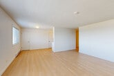 Located at 490 S State St in Bellingham, Washington, this one-bedroom, one-bathroom residence offers a thoughtfully laid-out single-floor plan with a clean, modern aesthetic throughout. Light wood-style flooring runs continuously across the space, lending warmth and visual cohesion to every room.

The open living and dining area is generously proportioned, featuring crisp white walls and a bright, airy atmosphere. Natural light filters in through multiple windows, including a large window in the living area that frames views of surrounding greenery. The bedroom is a comfortable, well-sized room with its own window overlooking the outdoors, a baseboard heater, and ample storage provided by two built-in sliding closets.

The galley-style kitchen is efficiently designed, offering white cabinetry from floor to ceiling, light countertops, a stainless steel sink, and a full suite of stainless steel appliances including a refrigerator, electric range, microwave, and dishwasher. A window at the end of the kitchen brings in additional natural light.

The bathroom is clean and functional, featuring a white vanity with an undermount sink, a toilet, and a shower. A central hallway connects the main living areas smoothly, with additional closet space tucked conveniently along the corridor. The overall ambiance is bright, neutral, and move-in ready.