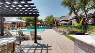 Located at 3560 Alma Road in Richardson, Texas, this residential community combines traditional brick architecture with thoughtfully designed outdoor living spaces. The exterior showcases warm red brick facades accented by arched entryways, stone detailing, and pitched rooflines that lend the community a timeless, classic character. Covered balconies and private outdoor spaces are integrated throughout the buildings, offering residents pleasant views of the surrounding grounds.

The centerpiece of the community is a generously sized resort-style swimming pool finished with striking blue tile work, reflecting the Texas sky and surrounded by a spacious deck outfitted with lounge chairs and shaded seating areas. A decorative water feature adds an elegant touch to the pool environment. Mature trees provide natural shade across the grounds, while manicured shrubs, ornamental plants, and vibrant landscaping create a lush, welcoming atmosphere throughout.

Wide concrete walkways and broad staircases with modern metal railings connect the various sections of the community, facilitating easy movement through the outdoor spaces. Decorative lamp posts and thoughtfully placed lighting enhance both the functionality and aesthetic of the grounds. The overall ambiance is one of comfort and sophistication, blending classic architectural design with resort-inspired outdoor amenities in a well-maintained setting.