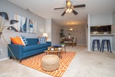 Located at 3800 Club Dr in Norcross, Georgia, this single-floor residence offers a thoughtfully designed layout with a cohesive contemporary aesthetic throughout. The spacious living room serves as the heart of the home, featuring a ceiling fan, carpet flooring, and an open connection to a dedicated sitting or flex area bathed in natural light from large windows framed by bold patterned curtains. The dining area, positioned adjacent to the kitchen, is highlighted by a statement pendant light and opens conveniently to the kitchen, which features dark cabinetry and a functional pass-through counter. The kitchen is well-equipped with ample cabinet storage and a built-in sink overlooking the dining space. Two well-proportioned bedrooms provide comfortable retreats, each with carpet flooring, ceiling-mounted lighting, and generous closet space. The primary bedroom includes a ceiling fan and windows that invite natural light. The bathrooms are clean and functional, featuring wide vanity countertops with dark cabinetry, bright overhead lighting, and wood-style flooring. A consistent neutral gray color palette, complemented by warm wood-tone flooring in key areas, gives the entire residence a modern and cohesive feel throughout.