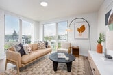 This well-appointed single-floor residence offers a thoughtfully designed layout that balances comfort and modern style. Light wood-look flooring flows throughout, connecting each area seamlessly. The open-concept kitchen is a standout feature, showcasing dark cabinetry, subway tile backsplash, stainless steel appliances, and a generous granite island with bar seating — ideal for both cooking and casual dining. The kitchen opens directly to the living area, which is bathed in natural light from expansive floor-to-ceiling windows and a sliding glass door that frame treetop and neighborhood views. The bedrooms are spacious and well-lit, each equipped with ceiling fans and large windows or sliding glass doors that invite abundant daylight and connect the interior to the outdoors. The bathroom is clean and functional, featuring a full tub-shower combination with white tile surround. A hallway entry with multiple doors provides access to closets and additional rooms, contributing to the home's practical flow. Recessed lighting throughout ensures a bright and welcoming ambiance. The overall aesthetic is contemporary and neutral, offering a versatile backdrop that complements a variety of interior styles.