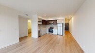 Located at 23 North Broadway Street in Tacoma, WA, this modern 2-bedroom, 1-bathroom unit offers a clean, contemporary design throughout. Light wood flooring runs continuously across the entire space, complementing the bright white walls and recessed lighting that create a fresh, airy atmosphere.

The open-concept living area flows directly into the kitchen, which features stainless steel appliances including a refrigerator, electric range, microwave, and dishwasher. Cabinetry combines dark upper cabinets with light lower units, accented by a tile backsplash and a sleek countertop workspace.

The primary bedroom benefits from expansive floor-to-ceiling windows that frame elevated views of Tacoma's urban streetscape, including the distinctive architecture of the surrounding North Broadway neighborhood. The second bedroom also features a large window with similar city views, filling the room with natural light. Both rooms are finished with clean white walls and consistent wood flooring.

A hallway lined with built-in floor-to-ceiling storage cabinetry connects the rooms efficiently, maximizing organization within the space. The bathroom is finished in an all-white palette, featuring a soaking tub with shower, a white vanity with an integrated sink, a large mirror, and wood-look flooring that ties the space together cohesively.