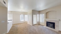 This well-appointed single-floor residence offers a thoughtfully designed layout that balances comfort and functionality. The expansive main living area immediately draws attention with its generous proportions, plush neutral carpeting, and an abundance of natural light streaming through multiple large windows fitted with vertical blinds. A tile-surround fireplace with a decorative arched niche above anchors one wall, adding warmth and architectural character, while a pendant light fixture highlights the adjacent dining area.

The kitchen is both practical and stylish, featuring white cabinetry, a marble-style countertop peninsula that opens toward the living space, stainless steel appliances including a refrigerator, range, and dishwasher, and wood-look flooring that ties the space together. Track lighting overhead and a window provide additional brightness.

The bedrooms are carpeted and well-lit, with each room featuring a ceiling fan and window with vertical blinds to allow natural light and airflow. The two bathrooms are finished with white vanity cabinetry, striking marble-style countertops, large wall mirrors with overhead lighting, and wood-look flooring. One bathroom includes a tub-shower combination, and both offer a clean, modern aesthetic throughout.