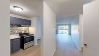 Located at 1175 Farmington Ave in Bristol, CT, this one-bedroom, one-bathroom residence offers a well-organized and functional layout across a single floor. The open-concept living room and kitchen area is anchored by light hardwood-style flooring and a baseboard heating system. A sliding glass door floods the living space with natural light and opens onto a private balcony overlooking a well-maintained courtyard with green landscaping and community seating areas. The kitchen is thoughtfully updated, featuring slate-blue cabinetry, a mosaic tile backsplash, white countertops, and a stainless steel refrigerator — a clean, modern aesthetic that complements the rest of the home. The spacious bedroom is carpeted for comfort and includes a large reach-in closet with built-in shelving, offering generous storage. A window brings in natural light and views of the surrounding complex. The full bathroom is finished with white subway tile wainscoting, a soaking tub with shower, a white vanity with under-cabinet storage, and wood-style flooring for a cohesive look. Multiple hallways connect the living spaces efficiently, and the layout flows naturally throughout. The overall ambiance is clean, bright, and move-in ready.