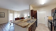 This single-story residence in Atoka, Tennessee offers a thoughtfully designed layout with two bedrooms and two full bathrooms. The open-concept living and dining area is anchored by wood-look flooring, neutral warm-toned walls, and large windows dressed with sheer curtains that allow natural light to fill the space comfortably.

The kitchen features dark espresso cabinetry, granite-style countertops, a double-basin sink set into a peninsula that overlooks the living area, and black appliances including a range, over-the-range microwave, and refrigerator. A dedicated laundry closet is conveniently located just off the kitchen. A separate dining area provides room for a full-sized table and chairs, ideal for everyday dining or entertaining.

The primary bedroom is carpeted and includes a ceiling fan and access to a walk-in closet. The primary bathroom is equipped with dark wood cabinetry, granite-style countertops, and wood-look flooring. The second bedroom offers a cozy, carpeted retreat. The second full bathroom features a tub-shower combination and matching cabinetry consistent with the rest of the home's finishes, maintaining a cohesive aesthetic throughout.