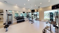 Located at 4101 Innovator Dr in Sacramento, California, this well-appointed fitness center is designed to support a comprehensive workout experience on a single level. The space is generously sized, offering an open, uncluttered layout that accommodates both strength training and cardiovascular exercise zones. Neutral-toned walls and light-colored flooring create a clean, modern aesthetic throughout, while recessed ceiling lighting ensures the entire area is well illuminated.

The strength training area is equipped with a robust selection of free weights, including multiple dumbbell racks, a cable machine, a multi-functional weight rack, and dedicated weight benches. Full-length wall mirrors enhance the sense of space and provide users with proper form feedback during workouts. A flat-screen television is mounted on the wall for added convenience.

The cardio zone features a variety of equipment, including treadmills, elliptical machines, a stationary bike, a stair climber, and a recumbent bike. Large arched windows along the perimeter flood this area with natural light and offer pleasant outdoor views of the surrounding greenery. Glass double doors provide direct access to the exterior.

A dedicated hallway off the main floor leads to separate men's and women's restrooms, including ADA-accessible facilities, ensuring the space is fully equipped for user comfort and accessibility.