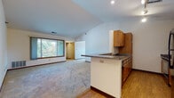 Located at 3110 S Fountain Square Blvd in New Berlin, Wisconsin, this single-floor unit offers a well-designed open-concept layout highlighted by vaulted ceilings that lend an airy, spacious feel throughout the main living area. The kitchen is positioned around a peninsula-style breakfast bar with a dark laminate countertop, warm wood cabinetry, a built-in sink, and stainless steel appliances including a refrigerator and range. Track lighting illuminates the kitchen, while recessed lighting accents the adjoining living space. Durable wood-look flooring runs through the kitchen and entry areas, transitioning to plush carpet in the living room and bedrooms.

The living area is generously proportioned, featuring a large sliding window that invites natural light and outdoor views. The bedrooms are carpeted and include windows with blinds, providing natural light and views of the surrounding greenery. Vaulted ceilings extend into select rooms, enhancing the open character of the unit. The bathroom features tile flooring, wood cabinetry with a dark countertop, and a well-appointed vanity with a mirror. A dedicated in-unit laundry closet houses a full-size washer and dryer, adding everyday convenience to the space.