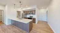 This well-appointed single-story home offers four bedrooms, one bathroom, and a thoughtfully designed layout that maximizes every square foot. The open-concept kitchen is a standout feature, showcasing rich medium-toned cabinetry, stainless steel appliances including a refrigerator, range, and microwave, white quartz countertops, a subway tile backsplash, and a large center island with pendant lighting — ideal for both cooking and casual dining. The kitchen flows seamlessly into the living area, which is brightened by natural light and sliding glass door access to a private balcony. Durable wood-look flooring runs throughout the main living areas, while the bedrooms are finished with plush carpet. The spacious primary bedroom includes generous closet space with built-in shelving and hanging rods. Additional bedrooms are well-sized with ample natural light and closet access. The bathroom features a wood-tone vanity with a white countertop and wood-look flooring. A dedicated laundry room houses a full-size side-by-side washer and dryer. Recessed lighting, clean white walls, and panel-style interior doors contribute to the home's modern, move-in-ready aesthetic throughout.
