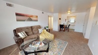 This single-floor residential unit offers a functional and comfortable layout designed to maximize livability. The open living area serves as the heart of the home, featuring wall-to-wall carpeting, large windows that invite abundant natural light, and ample room for both lounging and entertaining. A dedicated dining area sits adjacent to the living space, providing a seamless transition between the two zones.

The kitchen is efficiently designed with white cabinetry, light countertops, a stainless steel sink, and a gas range. A window above the sink overlooks greenery outside, adding a pleasant natural element to the cooking space.

The bedroom is generously sized, accommodating a full suite of furniture with ease. It features soft carpeting, a sliding-door closet offering practical storage, and a window that brightens the room with natural light.

A secondary room provides flexibility as a home office or additional bedroom, complete with carpeted flooring, a window with outdoor views, and sufficient space for a desk setup. The bathroom includes a shower-tub combination, a vanity, and tile flooring, rounding out this well-organized and practical living space.