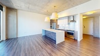 This contemporary 1060 square foot apartment in Kansas City offers a perfect blend of style and functionality. Located on the 24th floor, it boasts breathtaking views of the city skyline through floor-to-ceiling windows. The open-concept layout maximizes space and natural light, creating an airy atmosphere throughout.

The gourmet kitchen is a highlight, featuring sleek cabinetry, stainless steel appliances, and a large island with pendant lighting. The living area seamlessly connects to the kitchen, ideal for entertaining or relaxing while enjoying the panoramic views.

Both bathrooms exude luxury with marble-inspired tiling, glass-enclosed showers, and modern fixtures. The primary bathroom includes a double vanity with ample counter space and stylish lighting.

The bedrooms are generously sized, with the primary bedroom measuring 180 square feet. Each room features wood-look flooring and expansive windows. A walk-in closet with custom shelving provides abundant storage space.

Industrial-chic elements like exposed concrete ceilings and ductwork add character to the space, while the neutral color palette allows for personalization. This apartment combines urban sophistication with practical amenities, offering a premium living experience in the heart of Kansas City.