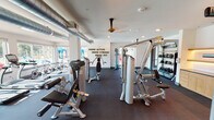 Located at 800 FM-1382 S in Cedar Hill, Texas, this fitness center is a thoughtfully designed, single-floor facility offering a comprehensive workout environment. The space is organized to accommodate a wide range of exercise disciplines, with clearly defined zones for strength training, cardio, and functional fitness.

The strength training area is outfitted with a full lineup of Hoist selectorized machines, a cable crossover unit, and a dedicated free weight section featuring a complete dumbbell rack and adjustable benches. A large framed mirror runs along one wall, enhancing the sense of space and allowing users to monitor their form. A wall-mounted rack holds kettlebells and medicine balls, supporting functional training routines.

The cardio zone includes stationary cycling bikes positioned near large windows, which bring in ample natural light and provide views of the surrounding outdoor area. Exposed HVAC ductwork runs along the ceiling, lending an industrial aesthetic that contrasts with the otherwise clean, white interior walls. Recessed lighting and ceiling fans maintain a comfortable atmosphere throughout.

A built-in cabinetry station with warm wood-toned finishes and under-shelf lighting adds a polished, practical touch, providing storage and counter space. The motivational phrase "Grow Active, Grow Strong, Grow Fit" is displayed prominently on the wall, reinforcing the facility's fitness-forward identity. Dark rubber flooring throughout ensures durability and safety.
