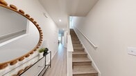 This two-story home offers a well-organized layout spread across two floors, with the larger share of living space situated on the upper level. The main floor hosts an open-plan living, dining, and kitchen area that serves as the social hub of the home. The kitchen is outfitted with white cabinetry, stainless steel appliances including a full-size refrigerator, microwave, and range, and light wood-look flooring that extends throughout. A rear-facing window brings in natural light and outdoor views. The dining area accommodates a full dining table and receives natural light through a large window. The living room features recessed lighting and flows seamlessly into the adjacent spaces. A dedicated office on this level provides a quiet workspace with a window. Four bathrooms are distributed across both floors to serve residents and guests efficiently. Upstairs, three bedrooms are connected by hallways, with the primary bedroom offering a comfortable, well-lit retreat with natural window light. Throughout, the home maintains a clean, neutral palette with white walls, light wood-look flooring, and panel-style interior doors, creating a bright and cohesive aesthetic.