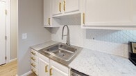 Located at 7 Dorchester Dr in Bethel Park, PA, this thoughtfully updated single-floor unit offers a clean, modern aesthetic throughout. Wood-look laminate flooring flows consistently across the living areas, bedrooms, and bathroom, lending a cohesive and contemporary feel to the entire space.

The open living and dining area is bright and welcoming, benefiting from large windows with vertical blinds that allow ample natural light to fill the room. Baseboard heating runs along the perimeter, and a wall-mounted air conditioning unit ensures year-round comfort. Neutral beige tones on the walls complement the light flooring throughout.

The kitchen stands out as a highlight of the unit, featuring crisp white cabinetry adorned with gold hardware, sparkling quartz countertops, a stainless steel sink with a pull-down faucet, and a distinctive white geometric tile backsplash that adds a stylish, modern touch.

The bedrooms are comfortably sized with the same wood-look flooring, neutral walls, and windows that bring in natural light and views of the surrounding greenery. The bathroom is clean and functional, offering a full tub-shower combination with brushed nickel fixtures, wood-look tile flooring, and a bright overhead light fixture. Crown molding accents select areas of the unit, adding a refined finishing touch throughout this well-maintained Bethel Park home.