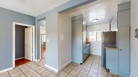 Located on S Ridgeley Drive in Los Angeles, CA, this single-floor, 2-bedroom, 1-bathroom residence offers a practical and efficient layout. The interior is finished with a cool blue-gray color palette throughout, creating a cohesive and calming ambiance across all rooms.

The galley-style kitchen is a standout feature, lined on both sides with tall, light blue cabinetry that maximizes vertical storage. Stainless steel appliances complement the cabinetry, while tile flooring and a window at the far end bring in natural light. The kitchen connects directly to the living area and hallway, facilitating easy flow throughout the unit.

Both bedrooms feature warm hardwood flooring and ceiling fans, contributing to a comfortable living environment. The primary bedroom includes mirrored sliding closet doors with built-in shelving and overhead storage cabinets, enhancing both storage capacity and the sense of space. Windows with blinds allow for natural light and privacy control. A wall-mounted air conditioning unit is also present in the bedrooms for climate control.

The bathroom is clean and bright, featuring a white tub-shower combination with a handheld showerhead, a single vanity with a mirror cabinet, and a small window for ventilation. The all-white finish gives the bathroom a crisp, functional appearance.

A connecting hallway ties all rooms together, making navigation intuitive within this efficiently designed home.