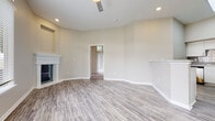 Located at 21480 Park Row Dr in Katy, TX, this single-story home offers a well-designed, open layout with a clean, neutral color palette throughout. The entryway welcomes you with light wood-look flooring that extends through the main living areas, vaulted ceilings, and large windows that allow natural light to pour in. The living room serves as a comfortable central gathering space, anchored by a classic white-mantled fireplace and a generously sized window with outdoor views. A sliding glass door in an adjacent carpeted room provides direct access to the backyard, further connecting the interior to the outdoors. The kitchen is thoughtfully equipped with white shaker-style cabinetry, white countertops, a grey subway tile backsplash, and stainless steel appliances including a range, over-the-range microwave, and refrigerator. A peninsula provides additional prep and dining space. The bedrooms feature plush wall-to-wall carpet and windows that bring in natural light, with at least one bedroom offering a connected bathroom. The bathrooms include a soaking tub with tiled surround and chrome fixtures, maintaining the home's consistent, clean aesthetic. Throughout, the space presents a bright, move-in-ready character well-suited to comfortable everyday living.