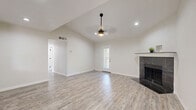 This well-appointed 2-bedroom, 2-bathroom single-story home in Round Rock, Texas offers a thoughtfully designed layout with modern finishes throughout. The living room is a standout space, featuring soaring vaulted ceilings, recessed lighting, a stylish pendant ceiling fan, and a striking dark marble-tiled fireplace that serves as a focal point. Light-toned wood-look flooring flows seamlessly throughout, complementing the bright, neutral color palette and creating a clean, cohesive aesthetic. A patio door fills the living area with natural light and provides access to the private outdoor patio.

The kitchen is well-equipped with gray shaker-style cabinetry, white quartz countertops, stainless steel appliances, a matte black faucet, and a geometric hexagonal tile backsplash. A pantry provides additional storage, and a window overlooks the exterior, bringing in natural light.

The primary bedroom offers a comfortable footprint with a large walk-in closet and a window framing views of the surrounding greenery. Both bathrooms are finished with bold dark marble-style tile surrounds in the tub/shower combinations and matte black fixtures, striking a modern contrast against the light flooring. Four closets throughout the home ensure ample storage, rounding out this move-in-ready residence.