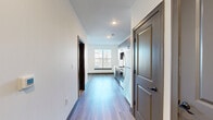 Located at 8310 N Green Hills Rd in Kansas City, MO, this one-bedroom, one-bathroom unit offers a thoughtfully designed single-floor layout that maximizes every square foot. Light wood-style flooring flows throughout the main living areas, complemented by crisp white walls and clean-lined dark baseboards that give the space a modern, cohesive aesthetic.

The entry hallway provides a welcoming transition into the open living area, where a ceiling fan and a window fitted with blinds bring in natural light and added comfort. The kitchen is a standout feature, showcasing dark wood-grain cabinetry with sleek black hardware, bright white quartz countertops, and a full suite of stainless steel appliances including a range, over-the-range microwave, refrigerator, and dishwasher.

The bedroom offers a cozy retreat with plush carpeting and a ceiling fan with a light fixture, alongside a window that invites natural light. The bathroom is well-appointed with a wide vanity featuring wood-tone cabinetry, white quartz countertop, an undermount sink, and a large mirror. Double doors lead to a dedicated closet, adding practical storage. The unit also includes a laundry area and utility room, rounding out a complete and functional living space.