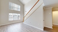 Located at 9807 Gable Ridge Terrace in Rockville, MD, this two-story home offers a thoughtfully designed layout across two floors. The main level makes a strong first impression with dramatic vaulted ceilings and an abundance of natural light streaming through stacked windows, creating an airy, open atmosphere. Light-toned hardwood-style flooring flows throughout the main level, complemented by neutral walls and clean white trim. A graceful staircase with a warm wood handrail and white balusters anchors the living space and leads to the upper floor. The galley-style kitchen is well-appointed with white shaker cabinetry, stainless steel appliances including a gas range and refrigerator, a undermount sink, and light countertops — all tied together by matching hardwood-style flooring. A dedicated laundry area with washer and dryer hookups adds everyday convenience. Upstairs, the two carpeted bedrooms feature vaulted ceilings, ceiling fans, and bright windows with outdoor views. The primary bedroom includes a spacious walk-in closet with wire shelving for ample storage, while the second bedroom also offers its own closet. The full bathroom is outfitted with a tiled tub-shower combination and hardwood-style flooring, keeping the design cohesive throughout.