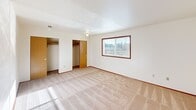 This two-story home in Puyallup, Washington offers a practical and well-organized layout spread across two floors of nearly equal size. The main floor houses the kitchen, living room, and hallway, while the upper floor accommodates the two bedrooms, two bathrooms, and closets. The kitchen is equipped with warm-toned wooden cabinetry, white appliances including a coil-top range and dishwasher, a double stainless steel sink, and light wood-style flooring — all topped with a textured ceiling. Ample upper and lower cabinet storage makes the space highly functional. Both bedrooms feature neutral carpet flooring and windows that allow natural light and neighborhood views. The spacious primary bedroom receives generous sunlight, lending it an open, airy feel. The bathrooms include a tub-shower combination with chrome fixtures and wood-style flooring. A dedicated utility room houses full-size washer and dryer hookups. The attached garage adds valuable storage or parking convenience. Three closets throughout the home provide practical storage solutions. The overall aesthetic is clean and straightforward, making this a well-suited home for those seeking functional living in a residential Puyallup neighborhood.