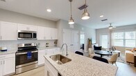 Located at 7600 Heron Cir in Vero Beach, Florida, this one-bedroom, one-bathroom residence offers a thoughtfully designed open-concept layout that maximizes its efficient footprint. The kitchen serves as a central hub, showcasing granite countertops on a peninsula island with bar seating, white shaker cabinetry, a classic subway tile backsplash, and stainless steel appliances. Stylish pendant lights with brushed brass accents illuminate the space with warm, modern character. The kitchen flows seamlessly into the dining area and living room, where light-toned wood-style flooring, soft sage-blue accent walls, and large windows create a bright, airy atmosphere. A ceiling fan and a private exterior door add both comfort and outdoor access to the living area. The bedroom features a bold navy accent wall, providing a cozy and refined retreat. The bathroom is clean and functional, appointed with full white tile surrounding a soaking tub-shower combination and wood-look flooring. A dedicated closet provides additional storage. Throughout the residence, the consistent use of neutral tones, contemporary fixtures, and natural light contributes to a cohesive and welcoming ambiance ideal for comfortable everyday living.