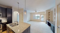 This single-story residence offers three bedrooms and two bathrooms within a thoughtfully designed open floor plan. The kitchen serves as a focal point, featuring dark espresso cabinetry extending to the ceiling, granite countertops, a subway tile backsplash, stainless steel appliances, and light hardwood-style flooring. A peninsula with a double undermount sink and pendant lighting connects the kitchen to the living area, which is finished with plush carpet, a ceiling fan, and sliding glass doors that invite natural light and outdoor views.

The bedrooms are carpeted and well-proportioned, each equipped with ceiling fans and windows offering exterior views. The primary bedroom features an arched doorway leading directly to its en-suite bathroom. Both bathrooms include granite-topped vanities with warm wood cabinetry, tiled flooring, and tub-shower combinations. A dedicated laundry room accommodates a full-size side-by-side washer and dryer with wire shelving above. Throughout the residence, neutral tones, arched doorways, and consistent finishes create a cohesive and comfortable living environment.