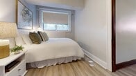 Located at 383–385 Wellington St W in Chatham-Kent, Ontario, this one-bedroom, one-bathroom unit offers a thoughtfully designed layout across a single floor. Light wood-tone vinyl flooring runs consistently throughout, creating a cohesive and clean aesthetic.

The living room features a drop ceiling with a paneled grid, natural light from windows fitted with blinds, and a welcoming atmosphere accented by rich dark-wood trim and a built-in shelving unit with a framed display case — a distinctive architectural detail that adds character to the space.

The kitchen is a standout, boasting white shaker-style cabinetry with matte black hardware, light granite countertops, a subway tile backsplash, and a full suite of stainless steel appliances including a refrigerator, electric range, and over-the-range microwave.

The bedroom is a calm and restful retreat, finished in neutral tones with a window offering natural light filtered through roller blinds. Clean baseboards and a minimalist design keep the room feeling open and serene.

The bathroom is neatly appointed with a tub and shower combination, a toilet, and wood-look tile flooring that continues the cohesive style of the unit. Overall, this unit presents a modern, well-maintained interior with practical amenities in a compact, efficiently organized floor plan.