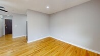 Located in Chicago's vibrant Lakeview neighborhood, this single-floor unit at 3161 N Cambridge Ave offers a thoughtfully organized layout comprising a living room, one bathroom, and two hallways. Warm-toned hardwood floors run throughout the main living area, lending a clean, cohesive aesthetic that brightens the space. The living room is the centerpiece of the unit, featuring recessed lighting, a ceiling fan, and a large window fitted with blinds that allows natural light to fill the room while offering views of the surrounding neighborhood. A wall-mounted HVAC unit provides convenient climate control year-round. The neutral gray walls complement the light hardwood floors, creating a calm and versatile atmosphere. The hallways connect the living area to the rest of the unit efficiently, with a closet providing practical storage. The bathroom is finished with light marble-style tile flooring, a white vanity with gold-toned hardware, a mirrored medicine cabinet, and a tub-shower combination — all presented in a clean, bright palette. The overall design of the unit is simple and functional, with consistent finishes throughout that make the space feel cohesive and well-maintained. Its location in the 60657 ZIP code places it within close proximity to the many dining, transit, and recreational amenities that Lakeview has to offer.