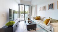Located in Toronto's M1W neighbourhood, this thoughtfully designed one-bedroom, two-bathroom unit offers a bright and efficient open-concept layout finished with warm hardwood flooring throughout. The kitchen features sleek white cabinetry, a classic subway tile backsplash, and a full suite of stainless steel appliances, flowing seamlessly into the dining area and living room. The living space is bathed in natural light through floor-to-ceiling sliding glass doors that open onto a private balcony with pleasant outdoor views. The generously sized primary bedroom continues the floor-to-ceiling glazing, framing treetop and skyline views, and connects to a hallway leading to a well-appointed bathroom. Two full bathrooms serve the unit: one features a glass-enclosed walk-in shower with vertical subway tile surround, while the second offers a full soaking tub with matching tile work. A dedicated in-unit laundry area and a closet add practical convenience. Clean white walls, recessed and track lighting, and a cohesive neutral palette give the entire space a modern, airy ambiance that makes efficient use of every square foot.