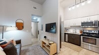 Located at 301 Church Ave in College Station, TX, this 4-bedroom, 2-bathroom unit is thoughtfully designed to maximize every inch of its compact footprint. The space features striking soaring ceilings that amplify the sense of openness throughout the shared living areas. Light-toned hardwood-style flooring flows seamlessly from the living room into the kitchen, creating a cohesive and inviting atmosphere.

The living room offers a wall-mounted TV and comfortable seating beneath impressively tall walls, while the adjacent kitchen is outfitted with stainless steel appliances — including a range, microwave, refrigerator, and dishwasher — paired with a two-tone cabinetry scheme of white uppers and dark lower cabinets, complemented by a tile backsplash and a single-basin sink.

Each bedroom is efficiently arranged, accommodating a bed with under-bed storage, built-in shelving, and a dedicated desk area, with windows allowing natural light to filter in. Both bathrooms feature a clean, modern aesthetic with gray vanities, white countertops, glass-enclosed showers, and light wood-style flooring. An in-unit laundry area with a washer and dryer adds everyday convenience. A connecting hallway ties all spaces together in a well-organized, functional layout.