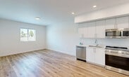 Located at 18355 SW 110th Ave in Miami, FL, this thoughtfully designed one-bedroom, one-bathroom residence offers a clean, modern aesthetic throughout. The open-concept layout seamlessly connects the kitchen and living area, creating a bright and functional shared space. The kitchen is well-appointed with sleek white cabinetry, white quartz countertops, and a full suite of stainless steel appliances including a gas range, built-in microwave, dishwasher, and a large French-door refrigerator. Recessed lighting illuminates the space, complementing the warm light wood-style flooring that extends throughout the unit. The spacious bedroom features a window with outdoor views of surrounding greenery, allowing natural light to fill the room. Two closets provide ample storage. The bathroom offers a clean, contemporary design with large-format neutral tile, a soaking tub with shower, a white vanity with an integrated sink, and recessed lighting. Additional conveniences include a dedicated laundry area and a utility room. The unit's crisp white walls and modern finishes create a bright, airy ambiance throughout.