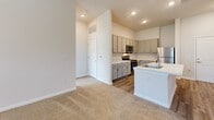 Located at 4225 East-West Connector in Smyrna, GA, this two-bedroom, two-bathroom unit offers a well-designed single-floor layout with a clean, modern aesthetic throughout. The open-concept kitchen is a standout feature, showcasing gray shaker-style cabinetry, light quartz countertops, a central island with an integrated sink, and a full suite of stainless steel appliances including a refrigerator, electric range, and over-the-range microwave. Wood-look luxury vinyl plank flooring runs through the kitchen and living areas, creating a warm, cohesive look. The living area flows naturally from the kitchen, benefiting from a ceiling fan and natural light from a nearby window. Both bedrooms are carpeted and well-lit, each with windows that frame views of surrounding greenery. The primary bedroom offers a comfortable, quiet retreat. The two bathrooms are finished with white subway tile walk-in showers and wood-look flooring, giving them a clean and contemporary feel. Three closets provide ample storage throughout the unit. A dedicated laundry area adds everyday convenience. Neutral tones and consistent finishes across all rooms contribute to a bright, move-in-ready atmosphere.