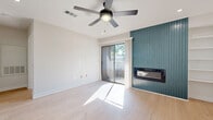 This thoughtfully designed single-floor residence offers a cohesive and modern aesthetic throughout, anchored by light wood-tone flooring that flows seamlessly from room to room. The open-concept main living area combines the living room, dining room, and kitchen into one bright, connected space. The living area is highlighted by a striking teal vertical-slat accent wall housing a sleek built-in fireplace, a ceiling fan with integrated lighting, and a sliding glass door that opens to a private outdoor balcony, filling the room with natural light. Built-in shelving adds functional display space along one wall.

The galley-style kitchen is efficiently designed with teal cabinetry, white quartz countertops, a classic white subway tile backsplash, a matte black pull-down faucet, and a full suite of stainless steel appliances, including a refrigerator, dishwasher, range, and microwave.

The bedroom features dual large windows that frame lush outdoor views and bathe the room in abundant natural light. Two closets provide generous storage. The bathroom is outfitted with a teal vanity with a white countertop, a framed mirror, matte black fixtures, and a tub-shower combination with full-height gray tile surround. A dedicated laundry area and hallway complete this well-appointed home.