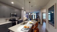Located at 1989 Cheshire Bridge Rd NE in Atlanta, Georgia, this single-floor residence offers a thoughtfully designed open-concept layout that seamlessly connects the kitchen, dining, and living areas. The kitchen is a standout feature, showcasing charcoal gray shaker-style cabinetry that extends to the ceiling, a classic white subway tile backsplash, stainless steel appliances including a gas range and built-in microwave, and a generous island with a white countertop, undermount sink, and bar seating illuminated by elegant pendant lights. Wood-look plank flooring flows throughout, tying the spaces together cohesively. The living room is bright and inviting, featuring large windows dressed in rich blue drapes, a ceiling fan, and access to an outdoor area. The bedroom continues the modern aesthetic with a bold accent wall, ceiling fan, ample natural light from large windows, and direct access to the bathroom and a walk-in closet. The bathroom is well-appointed with dark cabinetry, a white countertop vanity, a large framed mirror, and quality fixtures. Throughout the residence, recessed lighting and a neutral gray color palette create a polished, contemporary ambiance suited for comfortable urban living.