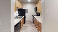 Located at 8121 236th St SW in Edmonds, Washington, unit S312 is a single-floor residence featuring a thoughtfully designed interior with consistent finishes throughout. The galley-style kitchen is outfitted with warm honey-toned cabinetry, light granite-style countertops, and wood-look flooring. Black appliances, including a refrigerator, electric range, and over-the-range microwave, are paired with a stainless steel sink, providing a functional and cohesive workspace. Ample upper and lower cabinet storage lines both sides of the kitchen corridor.

The living area features neutral carpet, a ceiling fan with light fixture, and a sliding glass door dressed with vertical blinds, allowing natural light to fill the space. A separate bedroom offers additional carpeted square footage, a window with horizontal blinds that frames a green outdoor view, and a wall-mounted heater unit. The full bathroom includes a maple vanity with granite-style countertop, a large mirror with overhead lighting, wood-look flooring, and a tub/shower combination. The overall palette is light and neutral, creating a clean, move-in-ready environment.
